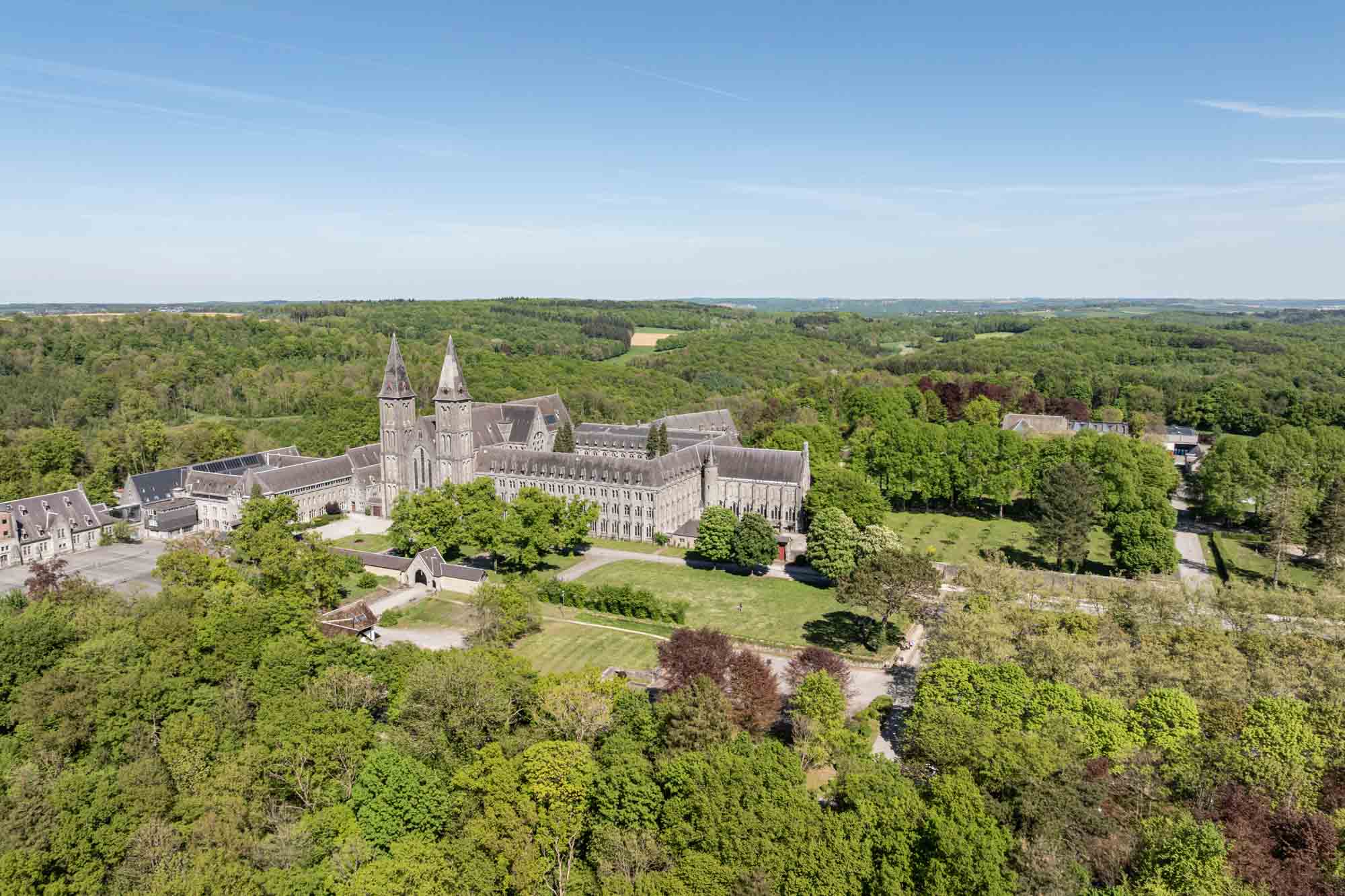 Abbaye de Maredsous vue du ciel entourée de forêts et de prairies verdoyantes